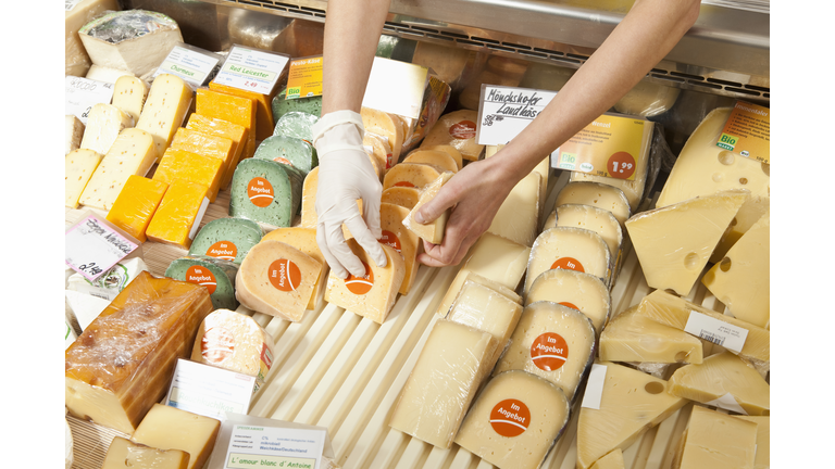 A sale clerk in a cheese shop, focus on hands