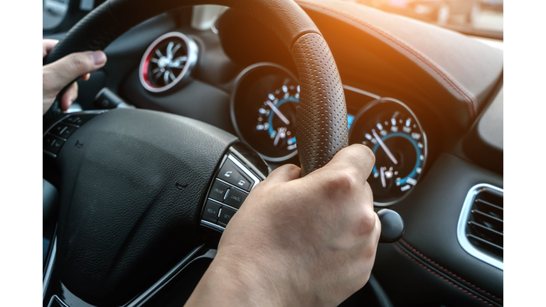 The driver controls the steering wheel in the car, and the car is driving.