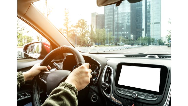 The driver controls the steering wheel in the car, and the car is driving.