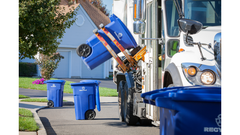 Recycling Truck Lifting Up Container Along Neighborhood Curb