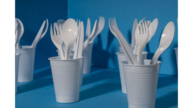 Disposable plastic tableware. Environmental problem, environmental pollution. On a blue background.