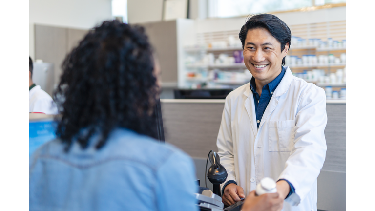 Male pharmacist assisting woman with prescription medication