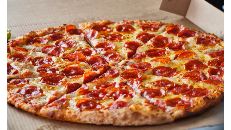 large american style pepperoni and cheese pizza in cardboard delivery box