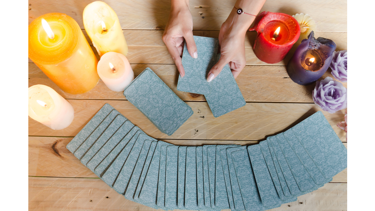 Fortune teller female hands and tarot cards on wooden table