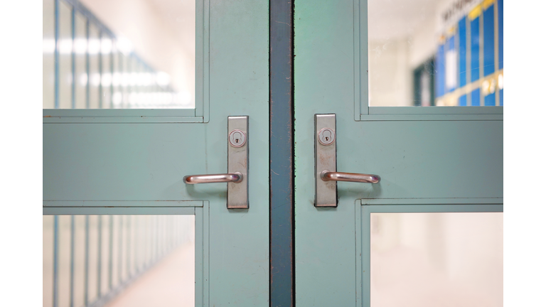 School closed due to Coronavirus. School closure under COVID-19 global pandemic. Selective focus on door and handle with blurred hallway, locker background. Fight against public health risk disease.