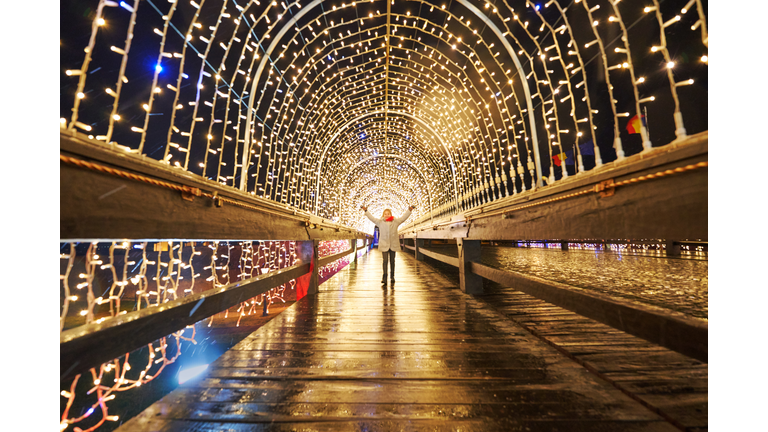 Girl admiring the tunnel with holiday lights, public lighting for the Christmas and New Year holidays