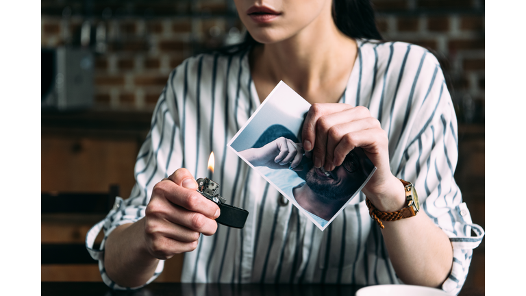 cropped shot of young woman burning photo card of ex-boyfriend