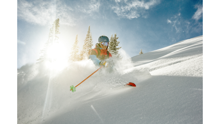 Skier takig a turn in deep powder on a sunny day.