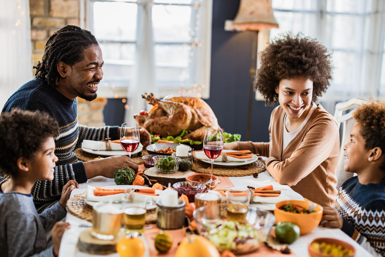 Happy African American family communicating while having Thanksgiving lunch in dining room.