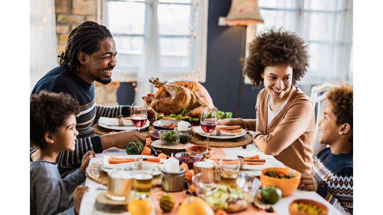 Happy African American family communicating while having Thanksgiving lunch in dining room.