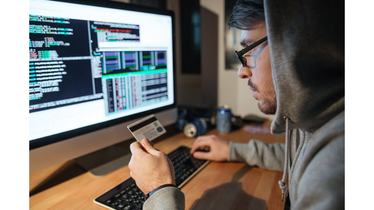 Concentrated hacker in glasses stealing money from diferent credit cards