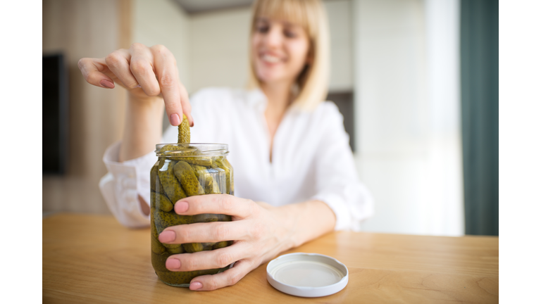 Pregnant woman eating pickles in kitchen