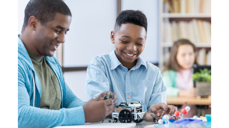 Mentor and male student working together on a robot