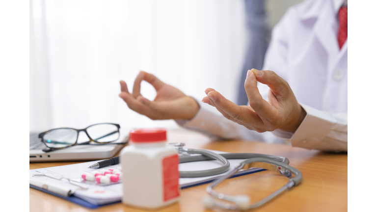 Doctor man wearing medical coat relax and doing meditation gesture with fingers. Yoga concept.