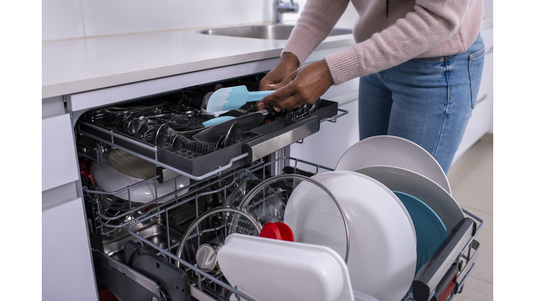 Woman unloading dishwasher after washing.