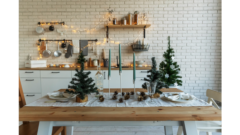 New Year and Christmas. Festive kitchen in Christmas decorations. Candles, spruce branches, wooden stands, table laying.