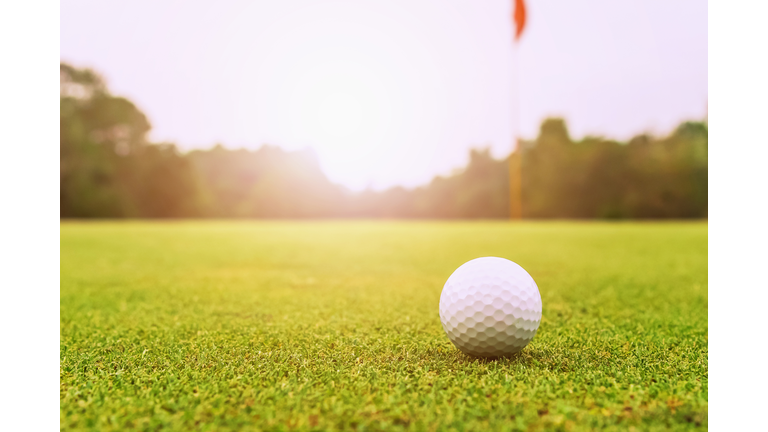 golf ball on green grass with sunrise