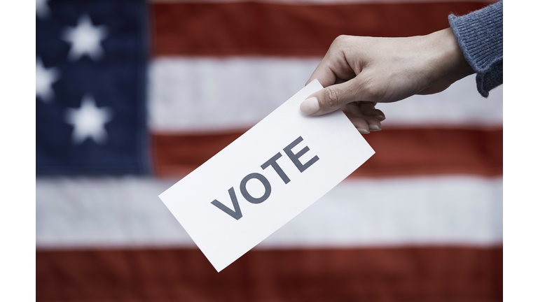 Woman holding paper with Vote text on American flag background