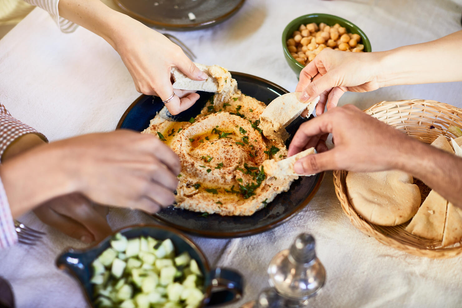 Vegan food, hands dipping hummus.