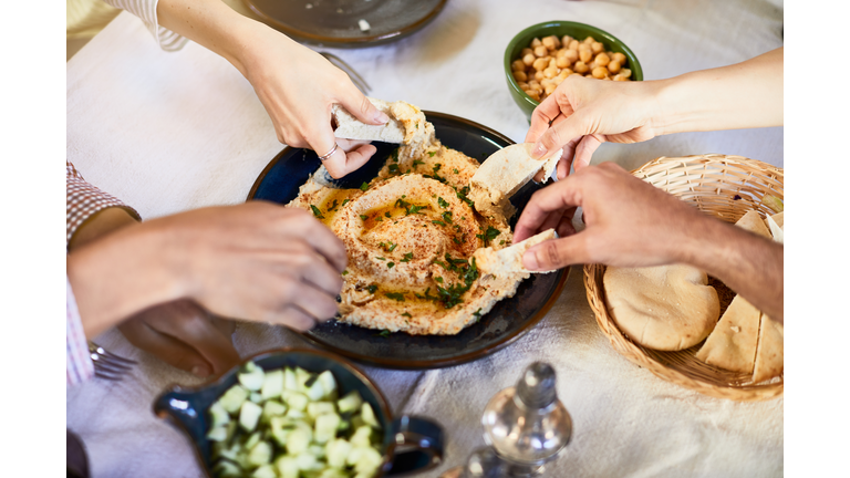 Vegan food, hands dipping hummus.