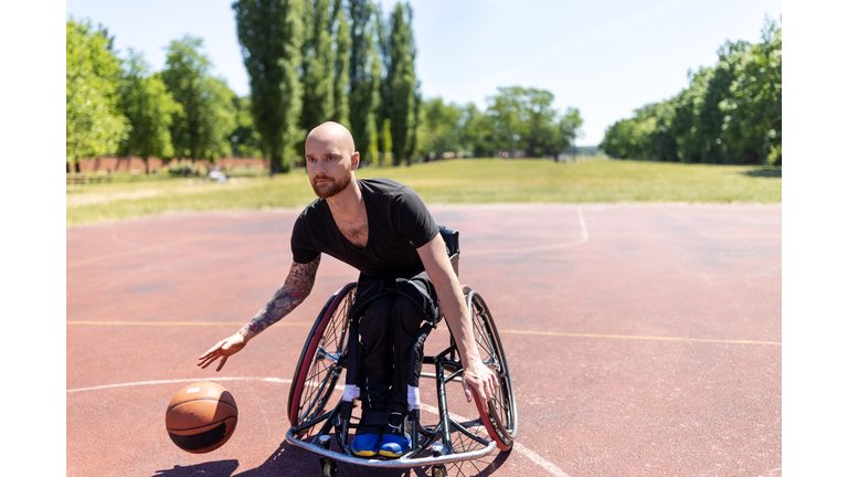Man in wheelchair playing basketball on outdoors court
