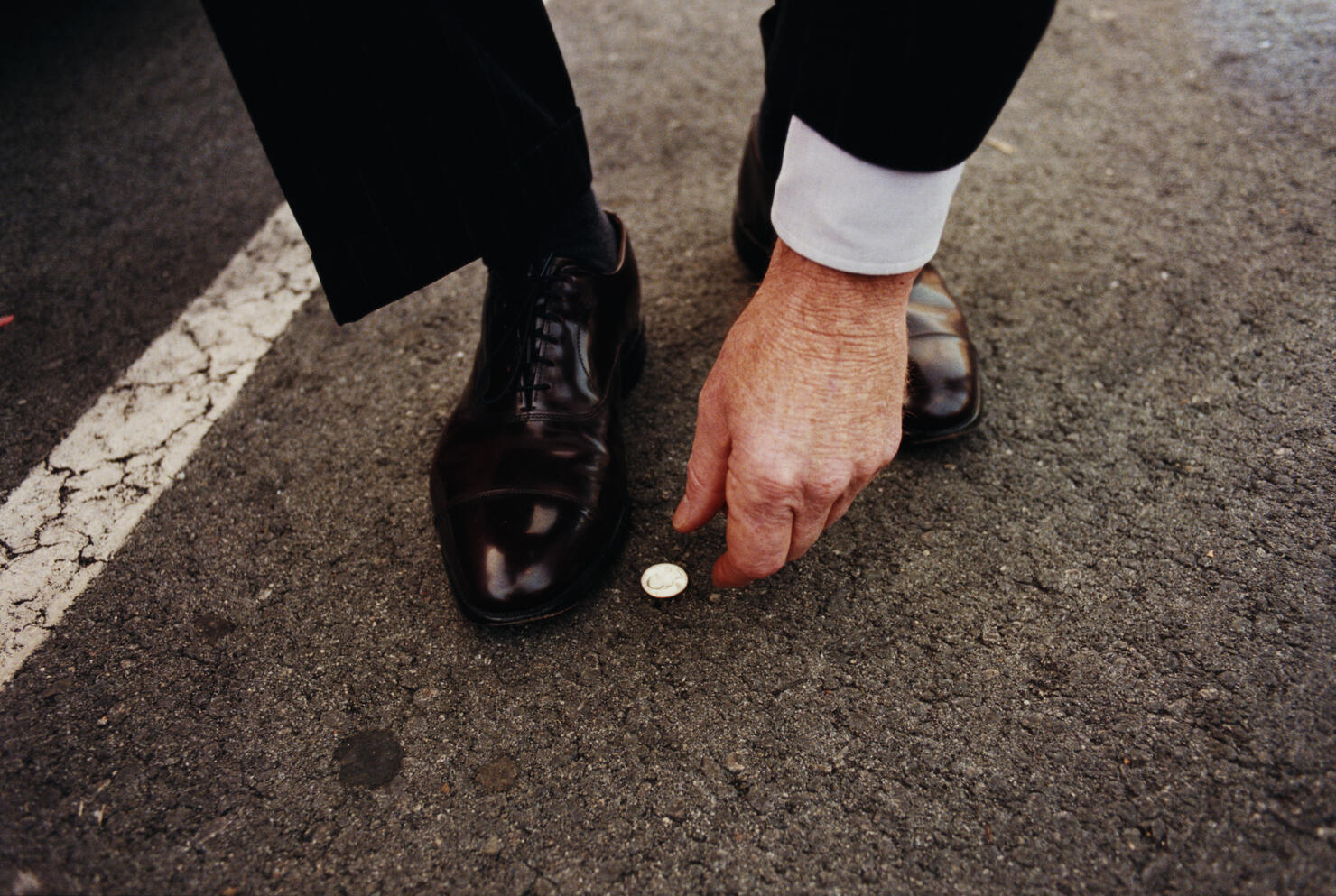 Man picking up coin from street