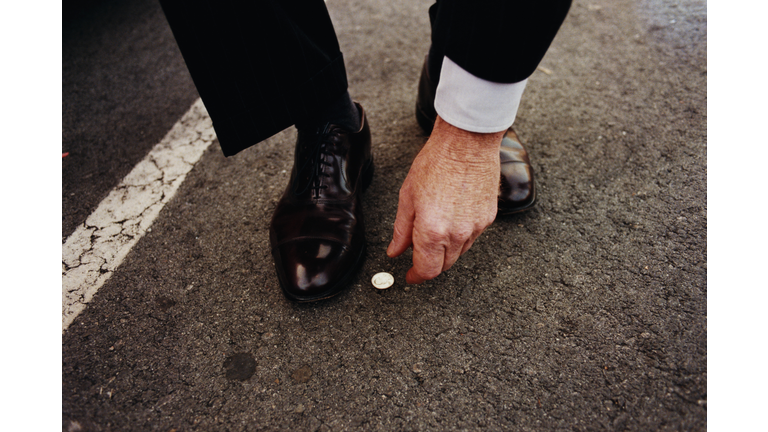 Man picking up coin from street