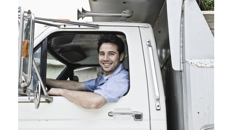 Caucasian man truck driver in company truck window.