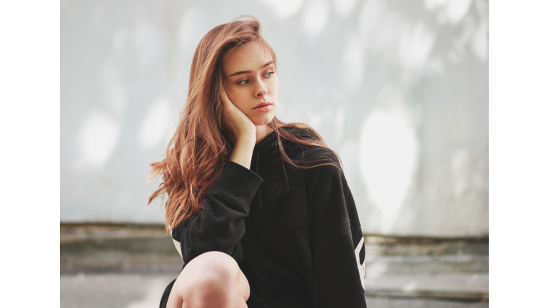 Sad Beautiful Woman Sitting Against Wall