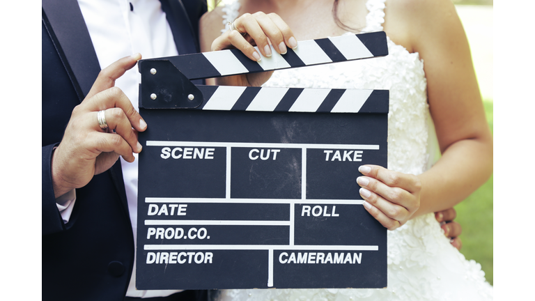 Happy beautiful bride and groom, woman holds clapper board, cinema board