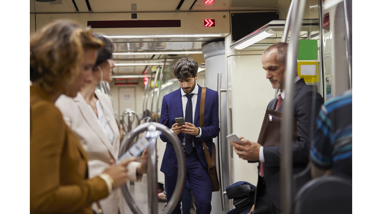 Businessman using cell phone on subway train