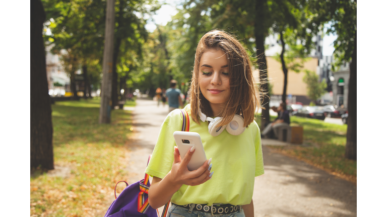 Happy beautiful young high school girl with white smart phone