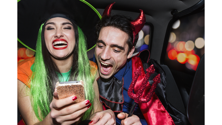 Halloween witch and devil laughing in back of car