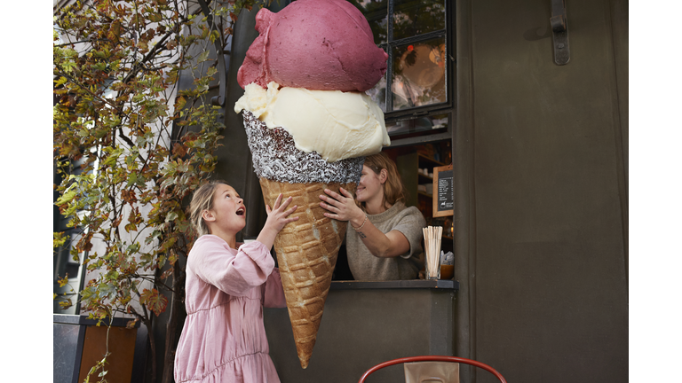 Girl buying large ice cream from take out counter of cafe