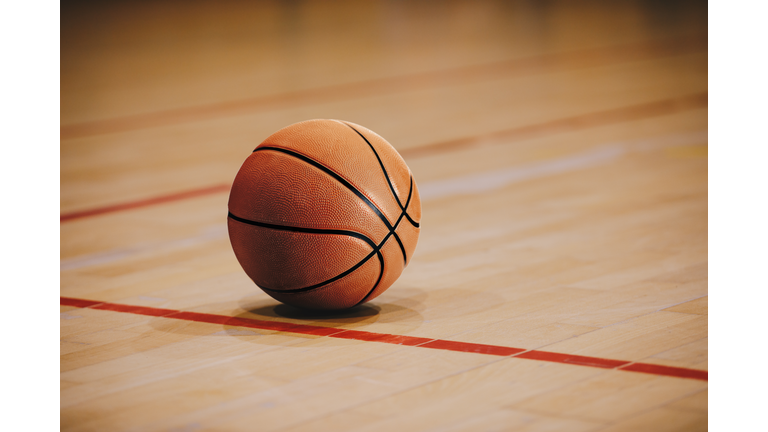 Classic Basketball on Wooden Court Floor Close Up with Blurred Arena in Background. Orange Ball on a Hardwood Basketball Court