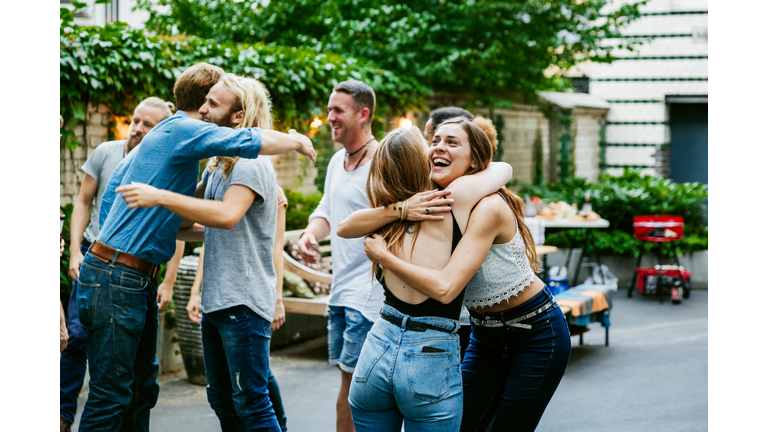 Young Group Of Friends Meeting Up For Barbecue, Hugging And Greeting Each Other.
