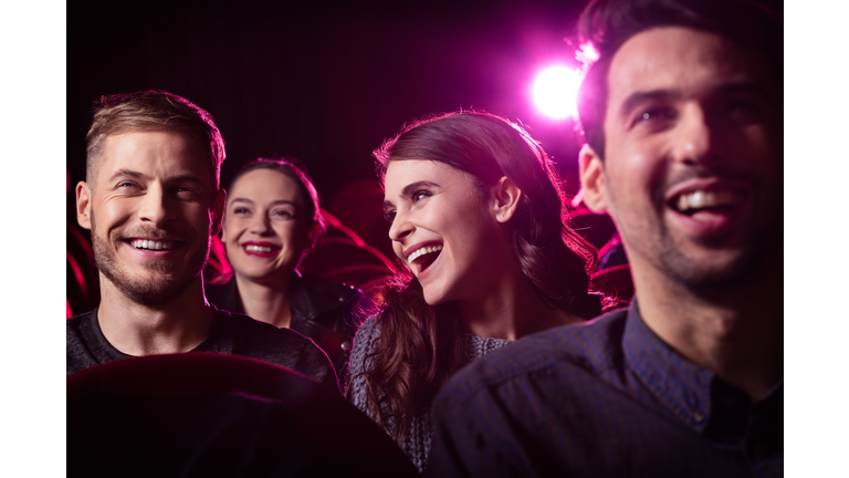 Happy friends watching movie in theater