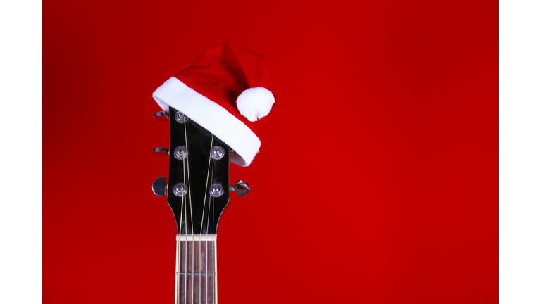 Christmas music concept. Acoustic guitar with steel strings and santa claus hat.