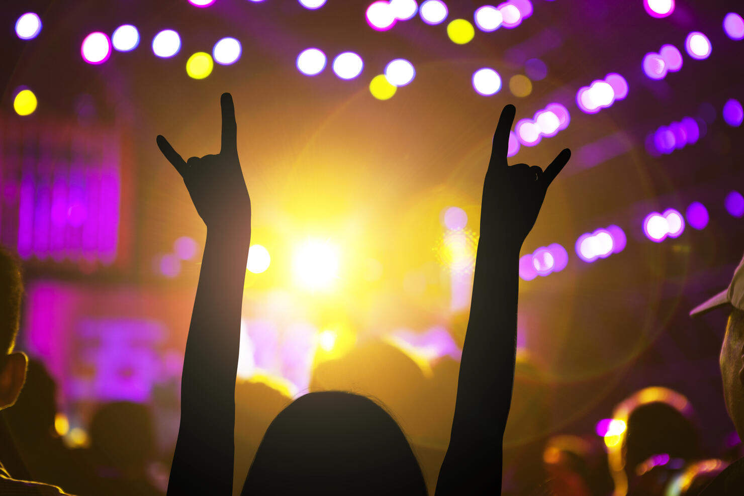 Woman dancing with arms raised at night club concert music festival