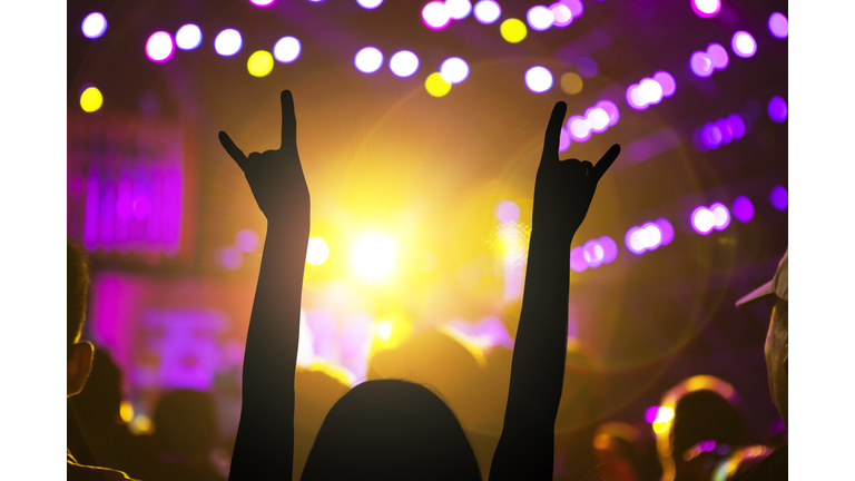 Woman dancing with arms raised at night club concert music festival