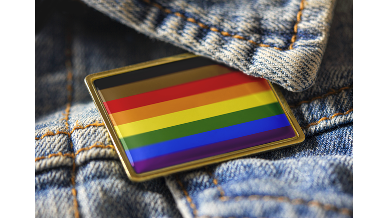 Philadelphia people of color inclusive flag pin on a denim jacket for LGBTQ identity, pride, and activism. The intersectional flag design is public domain for all uses.