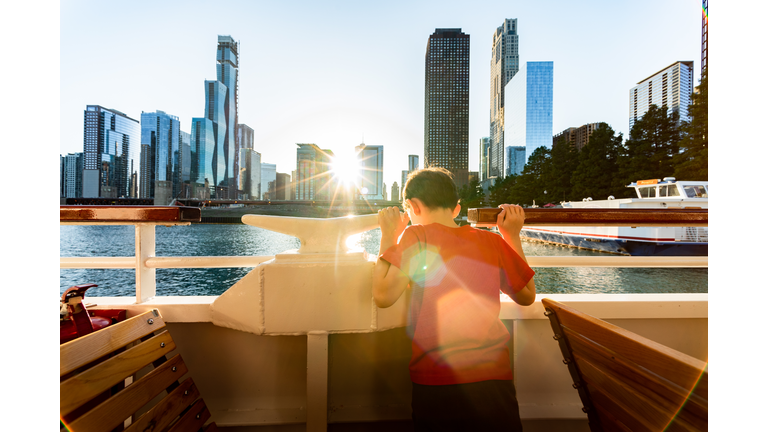 a boy on a boat looking down at the water with Chicago city skyline