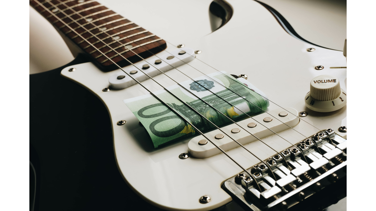 Money under the strings of a guitar. One hundred euros under the strings of a guitar.