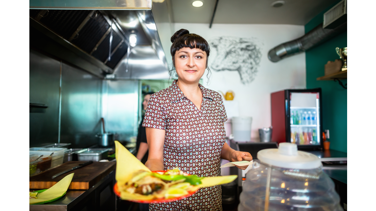Mexican Restaurant Owner Holding Out Plate of Food