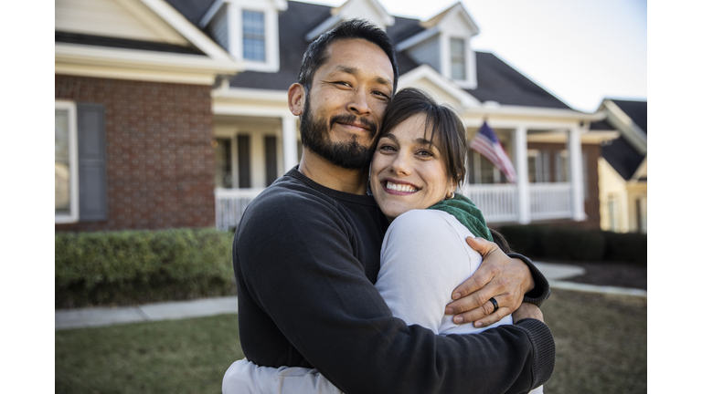Husband and wife embracing in front of home
