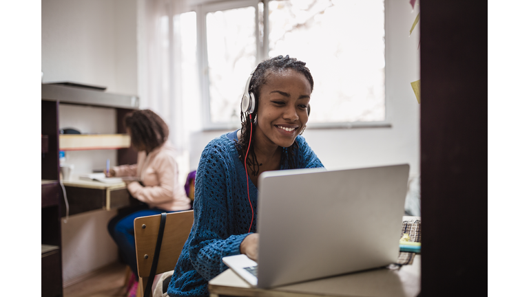 Young African female student , relaxing and listening music in a University campus room