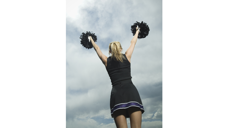Rear view of cheerleader with pom poms