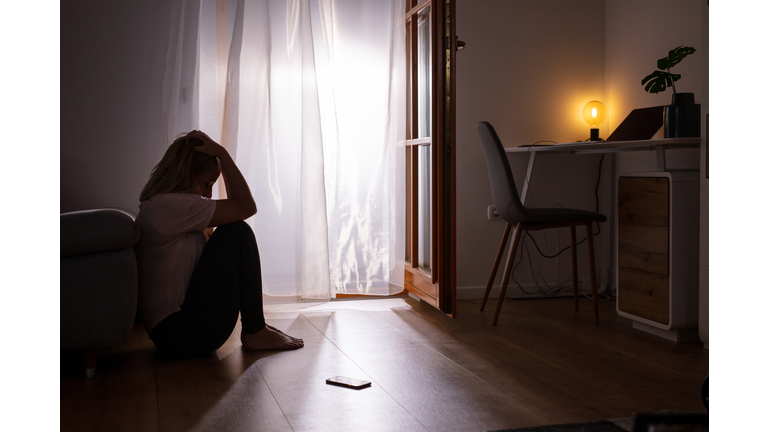 Sad depressed woman crying at home. Dark room.