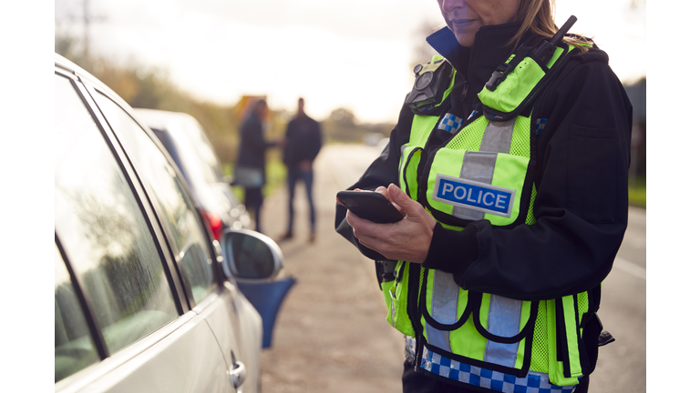 Female Traffic Police Officer Recording Details Of Road Traffic Accident On Mobile Phone