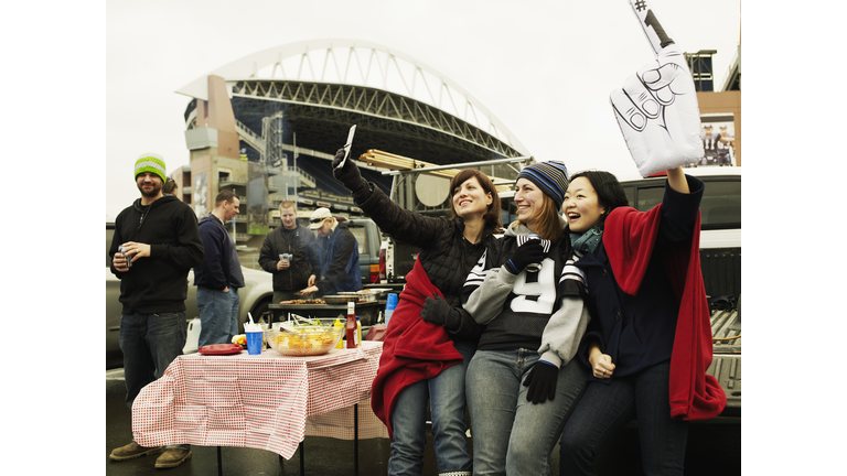 Friends taking self photograph at tailgate party